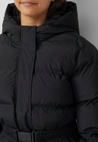 Zwarte pufferjack met een hoge kraag en capuchon. Heeft een taille met riem en zichtbare stiksels op de stof. Lichtgewicht, matte textuur.