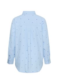 Chemise bleu clair à manches longues, motifs en forme de cœur en bleu plus foncé, détail empiècement au dos, et poignets à boutons. Texture de tissu lisse.