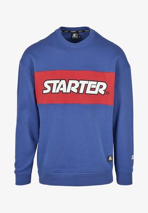 Kék pulóver piros vízszintes csíkkal, amelyen fehér betűkkel a "STARTER" felirat található. Kerek nyakú, hosszú ujjú, bordázott mandzsettákkal és hemel.