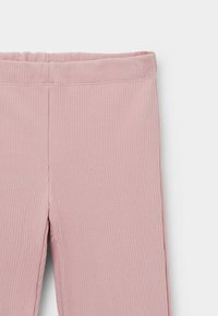 Leggings de color rosa claro con un cinturón elástico, que presentan una textura suave y un diseño ajustado que se extiende hasta el tobillo.