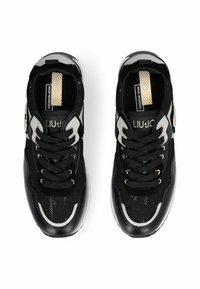 Baskets de sport noires en mesh et matériaux synthétiques, avec des accents argentés, des semelles épaisses et des lacets contrastants. Marquage visible sur la languette.