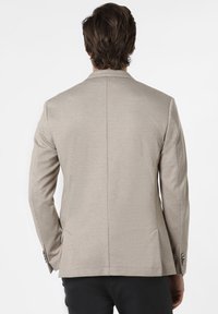 Beżowa marynarka w wzory o dopasowanym kroju, z pojedynczym rozcięciem z tyłu i mankietami na guziki. Teksturowany materiał w kratkę.