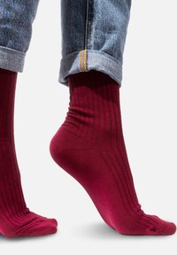 Burgundowe skarpetki w prążki o dopasowanym kroju, z gładką fakturą i wzmocnionymi ściągaczami, noszone ze podwiniętymi dżinsami.