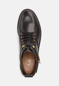 Bota de tornozelo em pele preta com ilhós dourados, bico redondo, atacadores e fecho lateral. Possui sola texturada e palmilha com marca.