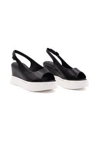 Sandali wedge neri in pelle con punta aperta, design slingback e suola piattaforma bianca con branding. Texture liscia e dettagli minimi.
