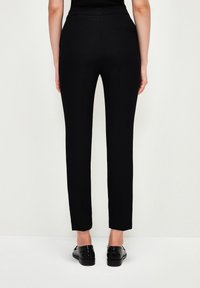 Svarta skräddarsydda byxor med slim fit, med en mjuk textur och minimalistisk design. En bakficka och enkel fåll.