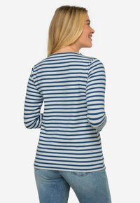 Blå och vit randig långärmad skjorta med rund halsringning, tillverkad av ett mjukt tyg med en figursydd design, i kombination med ljusblå jeans.