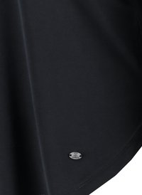Schwarzes T-Shirt aus glattem Stoff mit abgerundetem Saum und einem kleinen ovalen metallischen Logo-Tag in der unteren linken Ecke.