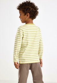 Long-sleeve striped shirt in light green and white, cotton material, round neck, worn with brown pants, displaying horizontal stripes.