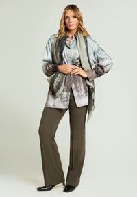 Jedwabna, wzorzysta bluzka w stonowanych odcieniach zieleni, brązu i szarości, zestawiona z oliwkowymi spodniami i czarnymi, spiczastymi szpilkami. Uzupełniona apaszką.