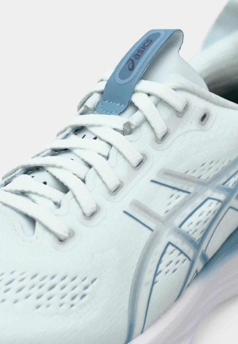 Chaussure de sport bleu clair avec une tige en mesh, des lacets ronds, une étiquette logo en plastique et une semelle blanche amortie avec des détails subtils.