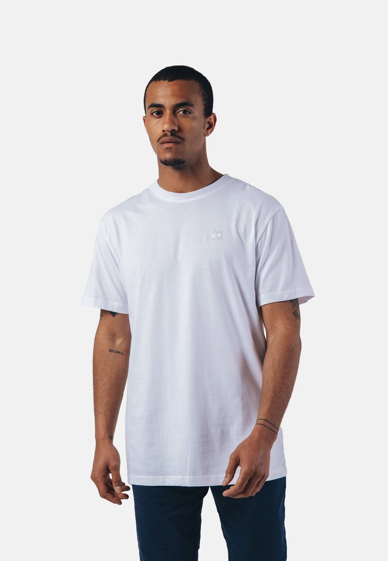 T-shirt en coton blanc avec un col rond, des manches courtes, et un petit logo d'éléphant brodé sur la poitrine. Coupe classique.