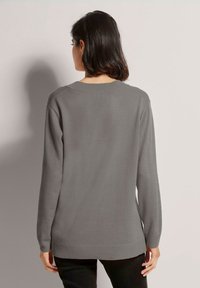 Grauer Strickpullover mit langen Ärmeln, geripptem Saum und Rundhalsausschnitt. Das Material wirkt weich mit einer glatten Textur.