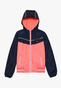 Větrnávka, která má námořnickou modrou a jasně korálovou barevnou kombinaci, se zipovým uzávěrem, kapucí a dvěma předními kapsami.