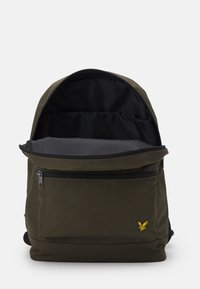 Zaino in tessuto verde oliva con una tasca frontale con zip e un ampio scomparto principale foderato in nero. Presenta un accento del logo giallo.