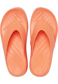Chanclas naranjas hechas de un material suave y flexible, con un diseño minimalista que presenta un dedo partido y una plantilla texturizada para mayor comodidad.