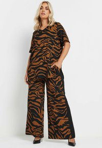 Top a strisce tigre marrone e nera con pantaloni a gamba larga, maniche corte e tasche laterali, realizzati in un tessuto morbido.