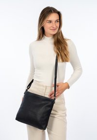 Borsa a tracolla in pelle nera con finitura texturizzata, forma piatta, tracolla regolabile e chiusura a zip sicura.