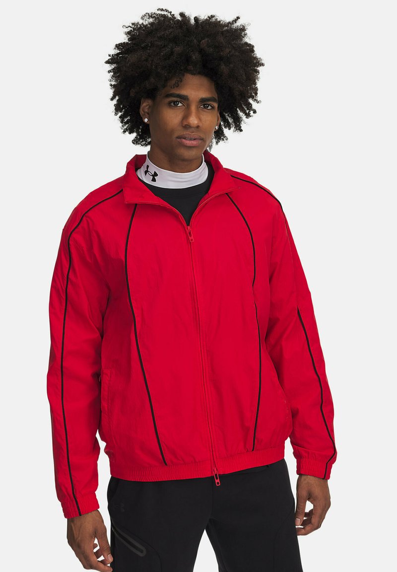 Rød zip-up jakke med sort piping, lavet af letvægtsstof. Har en høj krave og elastiske manchetter. Glat tekstur, afslappet design.