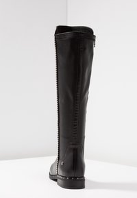 Stivale nero in pelle fino al ginocchio con texture liscia, dotato di cerniera laterale e dettagli con borchie sul tallone e sulla cucitura superiore.