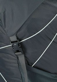 Materiale tessile nero con un motivo a griglia, dotato di una fibbia in plastica e di un cordino elastico. Include una tasca in rete sul lato.