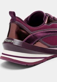 Baskets violettes avec une tige en mesh et textile brillant, présentant un design texturé et une semelle superposée avec des rayures blanches et violettes.