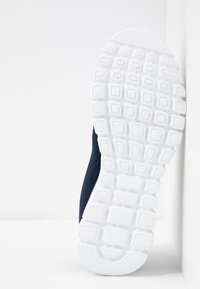 Námornícká atletická obuv s texturovaným textilním svrškem a bílou gumovou podešví se vzorem mřížky pro lepší přilnavost.