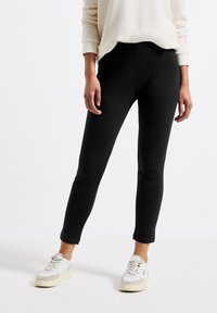 Leggings neri aderenti in un tessuto liscio ed elasticizzato, dotati di una vita alta e un design elegante. Abbinati a sneakers bianche.