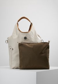 Cremefarvet taske med tekstur, brune læderhåndtag og en brun lynlås-pung placeret foran på en hvid overflade.