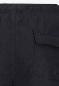 Pantalon cargo noir avec une taille élastique, doté d'une poche latérale et d'une texture lisse. Détails cousus le long des coutures.