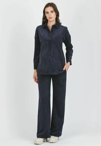 Set di abbigliamento da casa in blu navy realizzato in un tessuto morbido e texturizzato. Maglietta con colletto e maniche lunghe con bottoni, abbinata a pantaloni a gamba larga. Design casual.