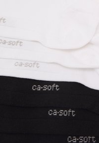 Tre paia di calzini impilati, due bianchi e uno nero. Ogni paio presenta la scritta "ca-soft" in grigio chiaro sul bordo, realizzata in un tessuto morbido e testurizzato.