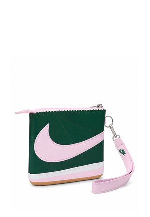 Piccola pochette rettangolare verde con grande logo Nike rosa, cerniera rosa e cinturino da polso rosa staccabile con logo Nike verde.