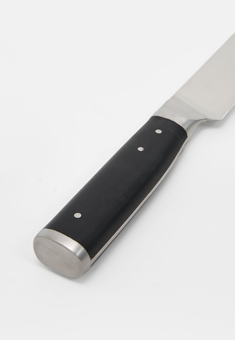 Couteau avec manche noir fixé par trois rivets en métal et un renfort en acier inoxydable, présenté sur un fond blanc.