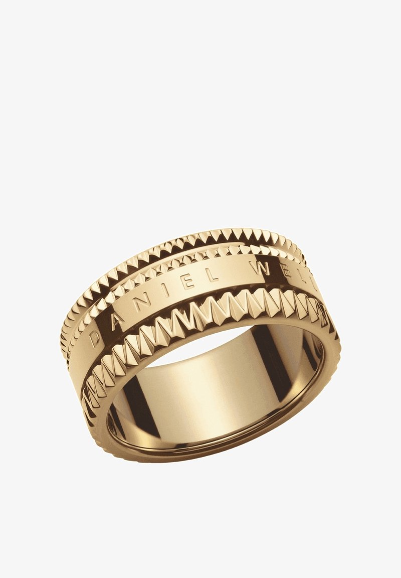 Bague en bande d'or avec des motifs triangulaires en relief sur les bords et « DANIEL WELLINGTON » gravé autour du centre.