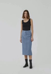 Sort ærmeløs top parret med en blå mønstret pencil skirt. Modellen har sorte ankelstøvler på. Baggrunden er ensfarvet og lys.