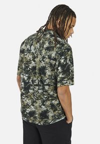 Korte mouwen shirt met een donker groene en zwarte abstracte patroon, gemaakt van lichte stof, met een losse pasvorm en een platte kraag.