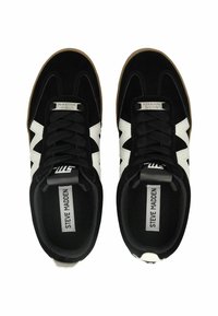 Sneaker in suede nera con dettagli bianchi e suola in gomma color caramelo. Design con lacci e etichettatura sulla linguetta e sul lato.