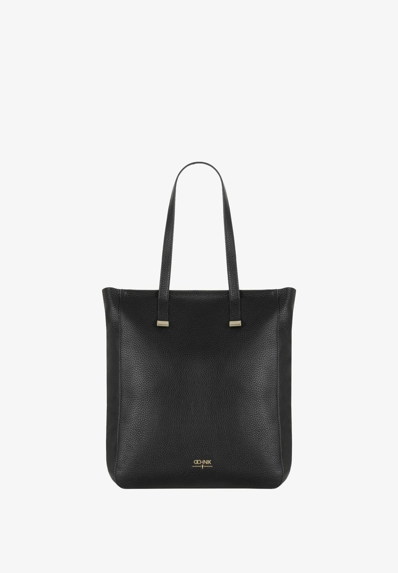 Czarna skórzana torba typu tote ma fakturowaną powierzchnię, podwójne górne uchwyty oraz akcenty w kolorze złotym. Prosta kwadratowa forma bez widocznych zapięć.