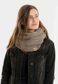 Gehaakte infinity sjaal in lichtgrijs, met een textuurpatroon. Draagt bij een zwarte denimjack, met drukknopen en zakken.