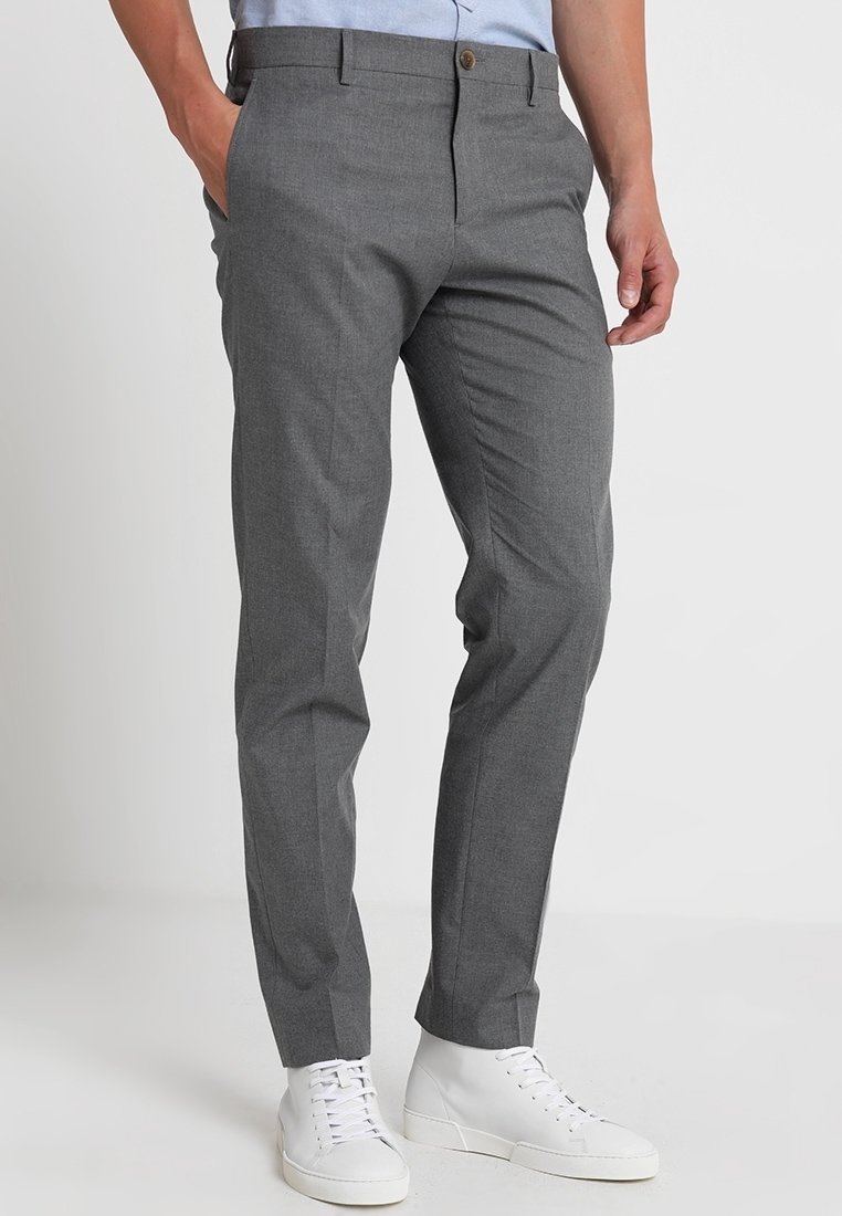Pantaloni grigi su misura realizzati in un tessuto testurizzato, con una linea dritta, passanti per la cintura e chiusura frontale con bottone, abbinati a sneakers bianche.