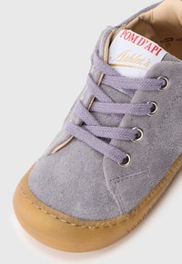 Grauer Wildleder-Sneaker mit lavendelfarbenen Schnürsenkeln, Gummisohle, gestickten Details und einem Etikett mit der Aufschrift "POM D'API Athlete's."
