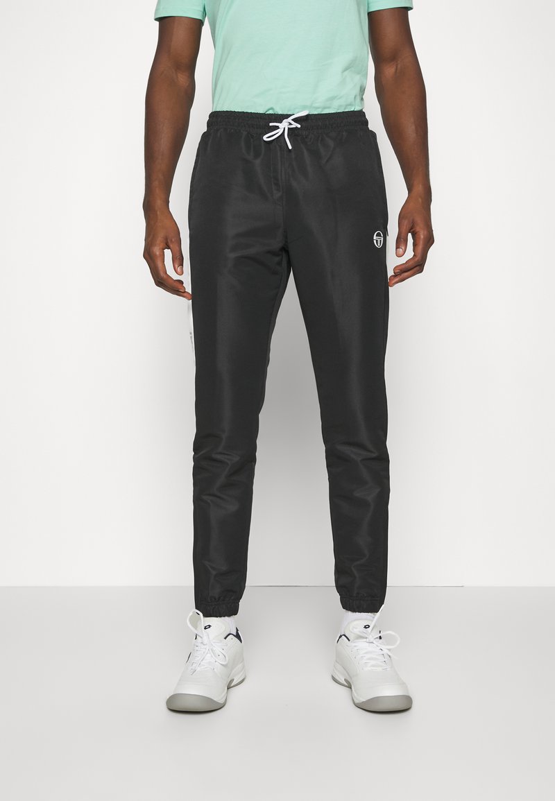 Zwarte sportieve broek met een elastische tailleband en witte koord, voorzien van een zijlogo en een taps toelopende pasvorm bij de enkels.