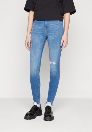 Blå skinny jeans i denim, med slitna knän och fransade fållar. Matchade med svarta lack skinn platåskor.