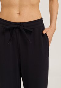 Mustat nauhalla kiristettävät housut, joissa on pehmeä rakenne, joustava vyötärö ja sivutaskut, leikattu rentoon istuvuuteen.