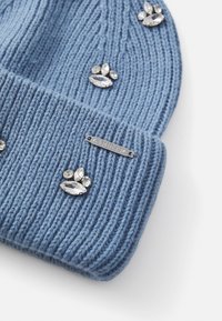 Cappello a maglia a coste blu chiaro con decorazioni di strass trasparenti e etichetta metallica "GUESS" in argento.