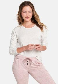 Ljusgrå långärmad topp med rund halsringning, kombinerad med rosa byxor med snodd i midjan som har tre knappar och sidofickor.