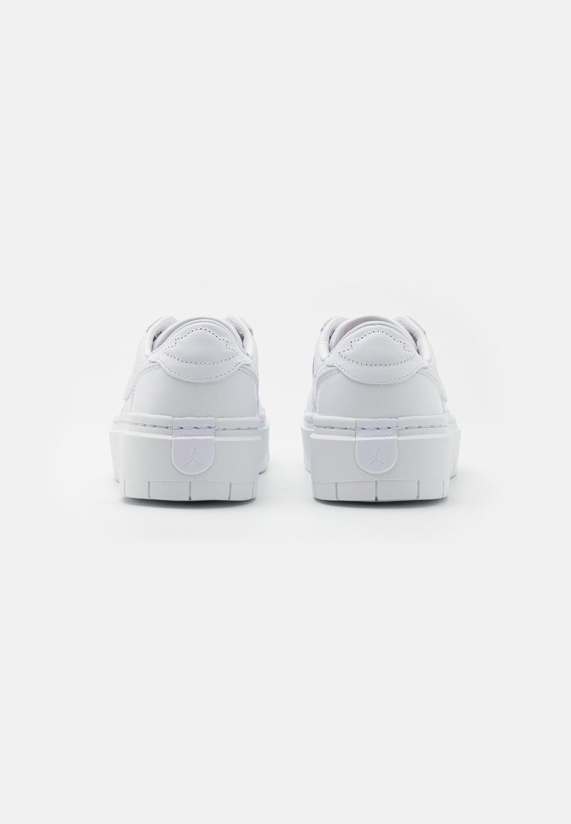 Baskets blanches avec une finition en cuir lisse, bout arrondi et semelle épaisse et texturée. Présente un détail de logo subtil sur le passant de talon.