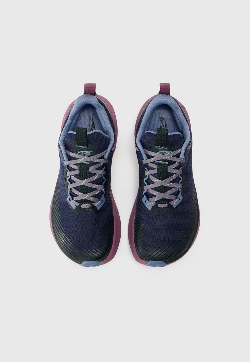 Zapatillas de running azul marino con una parte superior de malla texturizada, acentos morados, cordones grises y una suela duradera, que cuentan con una pestaña en el talón para facilitar el uso.