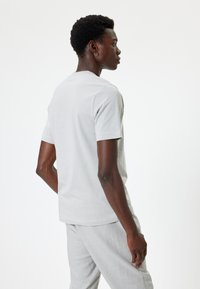 Lichtgrijs katoenen t-shirt met korte mouwen, ronde hals en een relaxte pasvorm. Soepele structuur met minimale naden en geen zichtbare patronen.